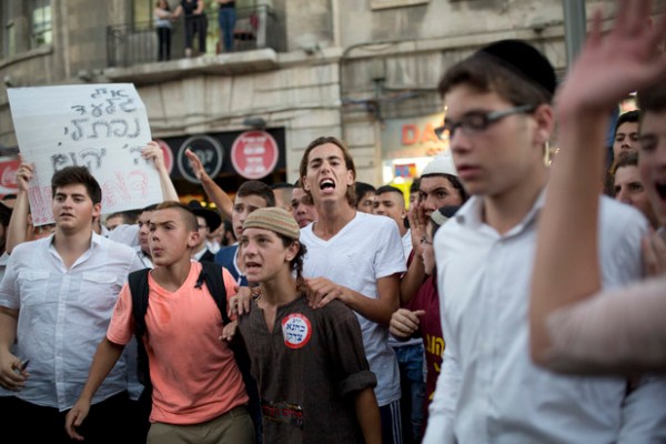  Lors d’une manifestation de la droite à Jérusalem, une pancarte proclame « Que Dieu venge leur sang » et un jeune porte un autocollant déclarant « Kahane avait raison », en référence au dirigeant du mouvement violent des colons, originaire de Brooklyn. 1er juillet 2014. (Tali Mayer/ActiveStills)