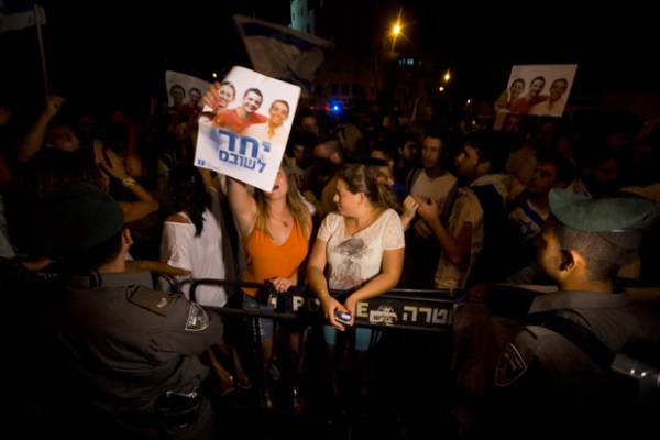 Des manifestants de droite crient des slogans anti-palestiniens lors d’un rassemblement devant la résidence du Premier ministre israélien à Jérusalem, le 5 juillet. Les manifestants lèvent des affiches montrant les trois adolescents assassinés avec le texte, « Unis pour les ramener chez eux ». (Faiz Abu Rmeleh/ActiveStills)